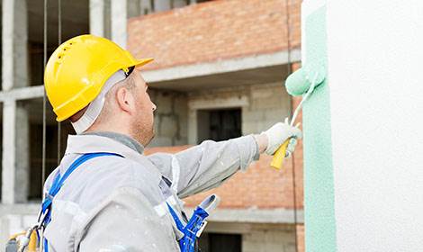 Schilder met helm die het buitenschilderwerk verzorgt